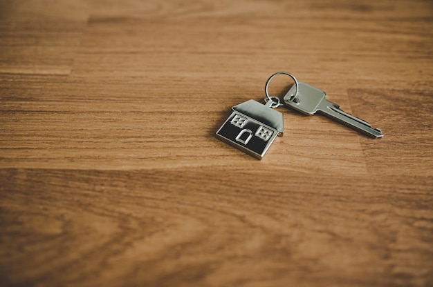 Sleutel en een huis in de vorm van een sleutelhanger op houten vloer in de kamer