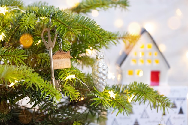 Sleutel tot het huis met een sleutelhanger hangt aan de kerstboom Een cadeau voor nieuwjaar Kerstmis Bouwontwerpproject verhuizen naar een nieuw huis hypotheek huren en onroerend goed kopen Ruimte kopiëren