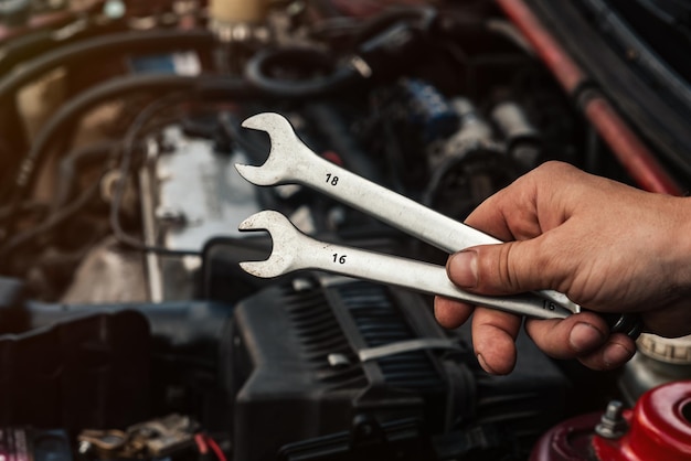 Sleutels in de wizards hand close-up tegen de achtergrond van de auto wordt gerepareerd concept van een