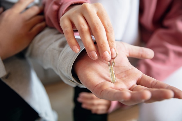 Sleutels ophalen van nieuw huis. Nieuwe eigenaren van onroerend goed, jong stel verhuizen naar nieuw huis, appartement, close-up van handen. Droom, liefde, relatie, onroerend goed en interieurconcept. Nieuw leven samen.