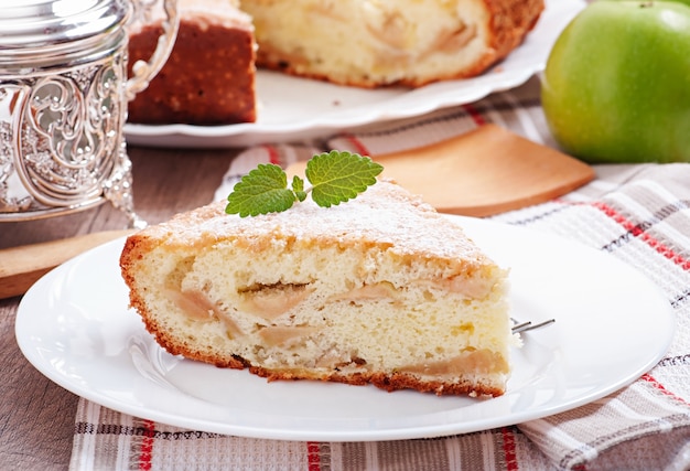 Slice of apple fruit pie on a plate decorated with mint leaf