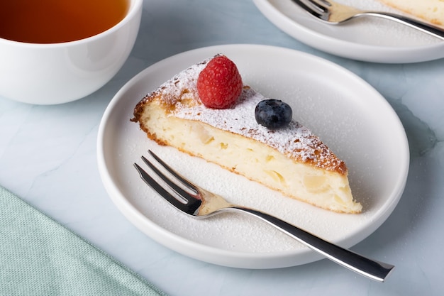 Slice of apple pie with powdered sugar garnished with raspberries and blueberries