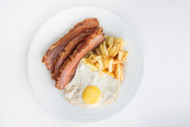 Slice of bacon, egg and potatoes chips in white background