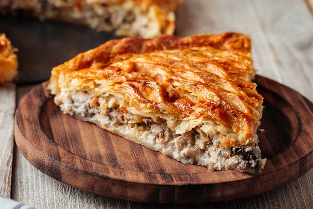 Slice of baked meat pie on wooden plate