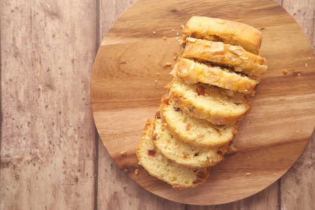 Slice of bakery fruit cake on chopping board