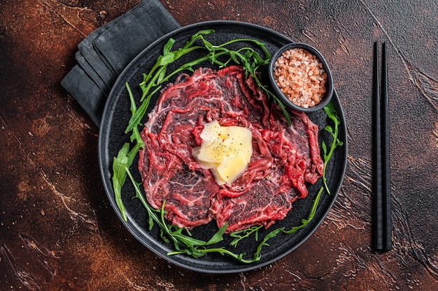 Slice Of beef Carpaccio, arugula and Parmesan. Dark background. Top view.