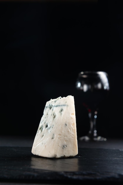 Slice of blue mold cheese roquefort cheese on a dark background closeup view with copy space