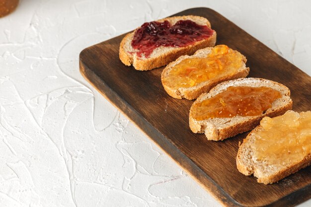 Slice of bread covered with fruit jam on wooden board 