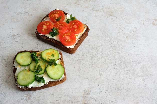 A slice of bread with cucumber and tomato slices and cream cheese isolated closeup