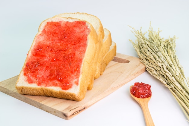 Photo slice bread with strawberry jam on cutting board