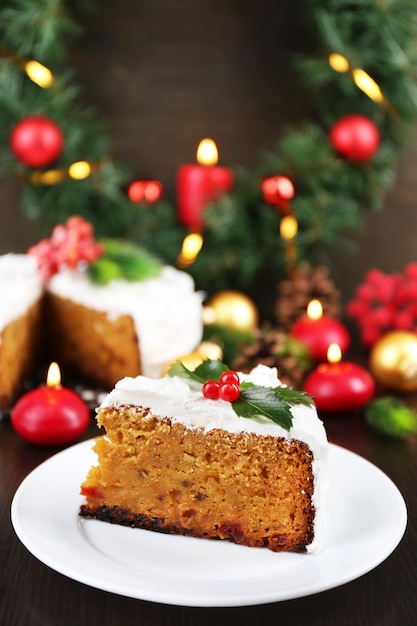 Slice of cake covered cream with Christmas decoration on wooden table background