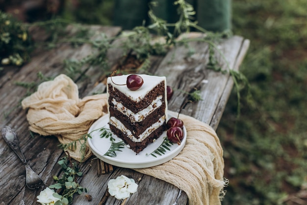 Slice of cake decorated with cherry on a wooden table