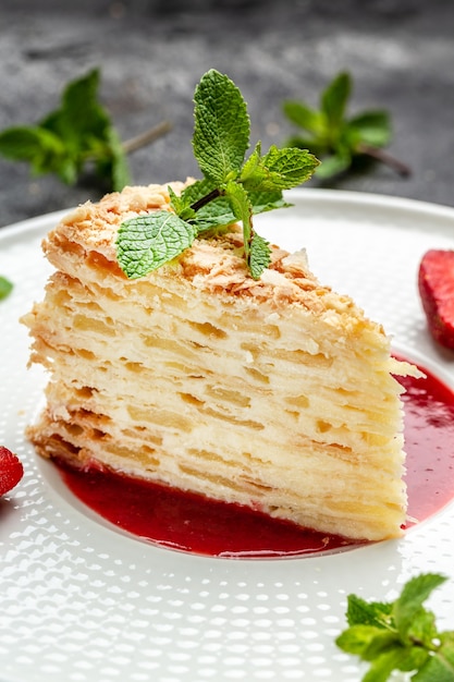 Slice cake of puff pastry with cream, apples and strawberry jam decorated mint. Delicate and airy cake. vertical image. top view