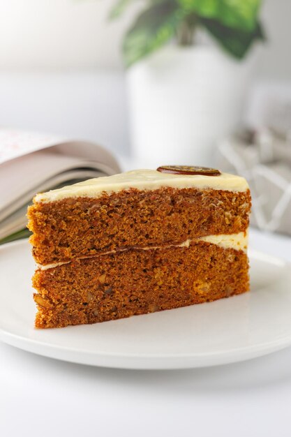 Foto una fetta di torta di carota su un piatto bianco con un libro sullo sfondo