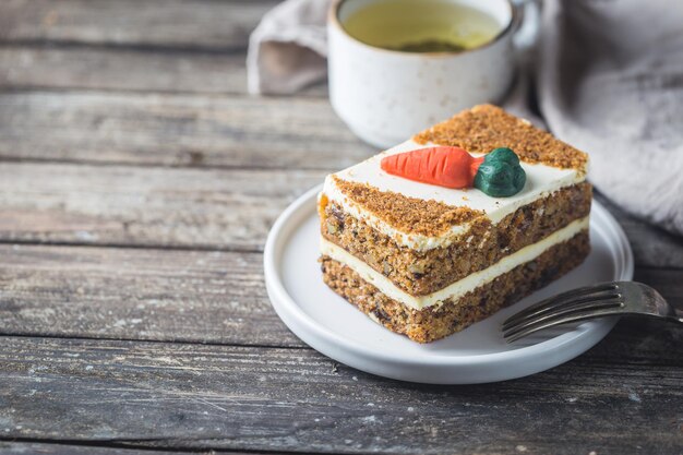 Slice of carrot cake with cream cheese frosting on wooden table