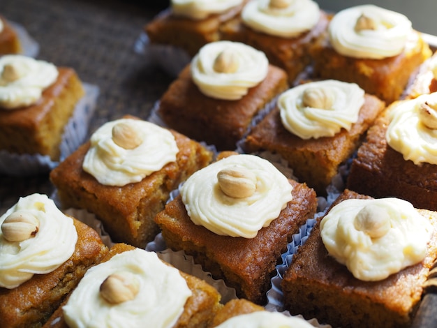 Slice of carrot cake with cream cheese frosting on wooden tray