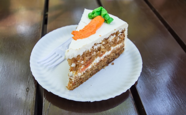 Slice of carrot cake on wood background