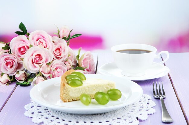 Slice of cheesecake with grape berries on plate on wooden table on bright background