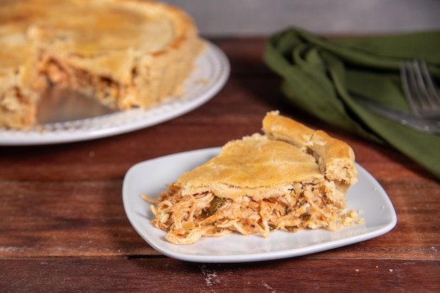 Foto una fetta di torta di pollo su uno sfondo di legno rustico