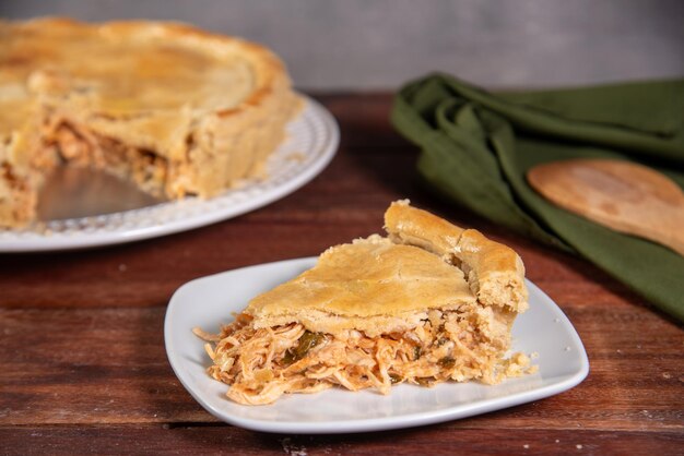 Foto una fetta di torta di pollo su uno sfondo di legno rustico