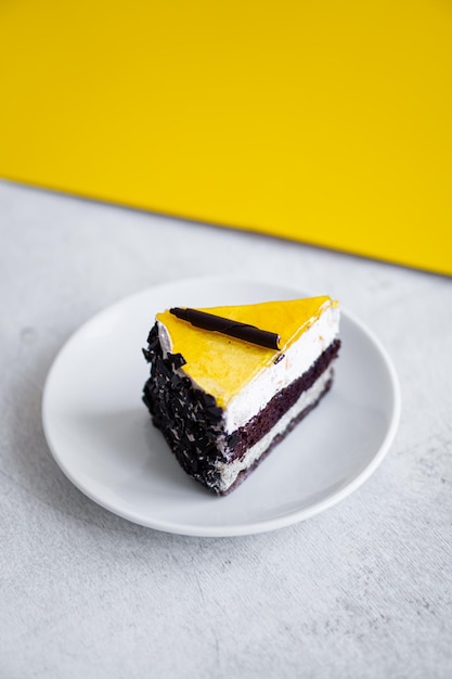 Кусок шоколадного торта с желтым желе сверху на белом столе