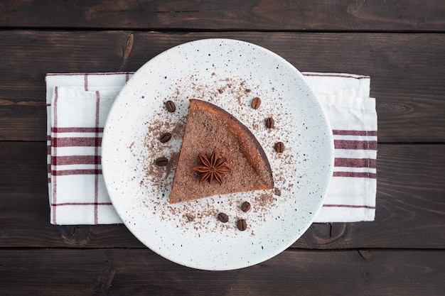 Fetta di casseruola di cagliata al cioccolato su un piatto, una fetta di torta con cioccolato e caffè. fondo rustico in legno scuro. vista dall'alto lo spazio della copia