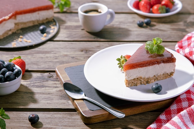 Fetta di cheesecake classica servita su piatto bianco su tavola di legno. messa a fuoco selettiva.