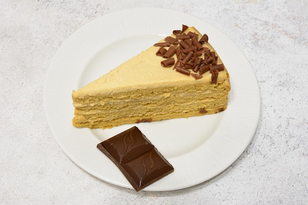 A slice of coffee cake with chocolate bar on a white saucer isolated