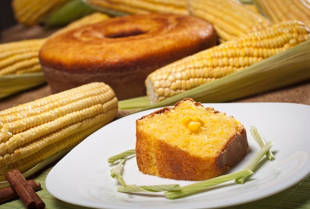 Photo slice of corn cake on green bamboo mat and cake and corn in the background.