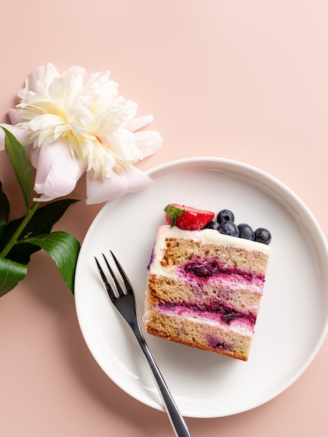 Slice of delicious cake with blueberry filling and peony flower Sweet layered cake