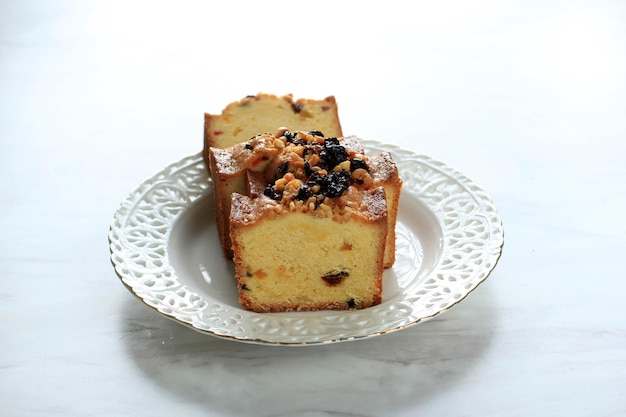 Slice of delicious homemade english fruit cake loaf pudding\
with dried mixed fruit, sultanas, raisins, and chopped almond.\
served during christmas party or new year eve. isolated on\
white