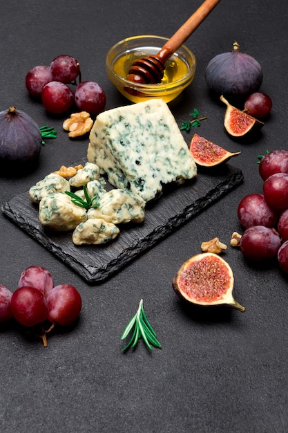 Slice of French Roquefort cheese and fruits on stone board