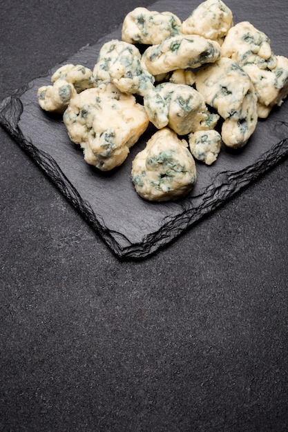 Кусочек французского сыра рокфор на каменной доске