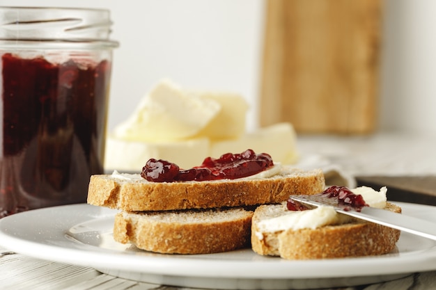 Slice of fresh bread with butter and jam on table