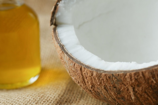 Slice of fresh coconut and bottle of oil on a table