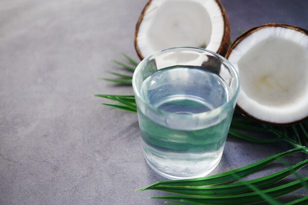 Slice of fresh coconut and glass of coconut water on table