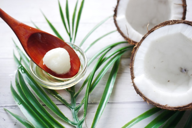 Slice of fresh coconut and oil on spoon on table