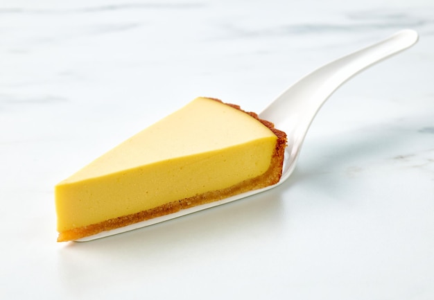 Slice of fresh vegan mango cake on light kitchen table