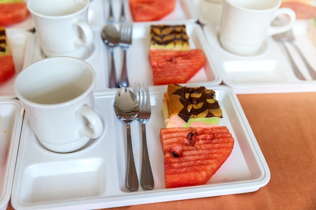 Slice of fresh watermelon with piece of cake and empty cup of coffee.