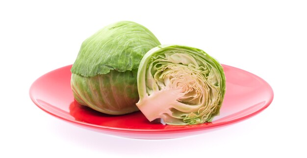 白い背景で隔離の皿に緑のキャベツをスライスします。