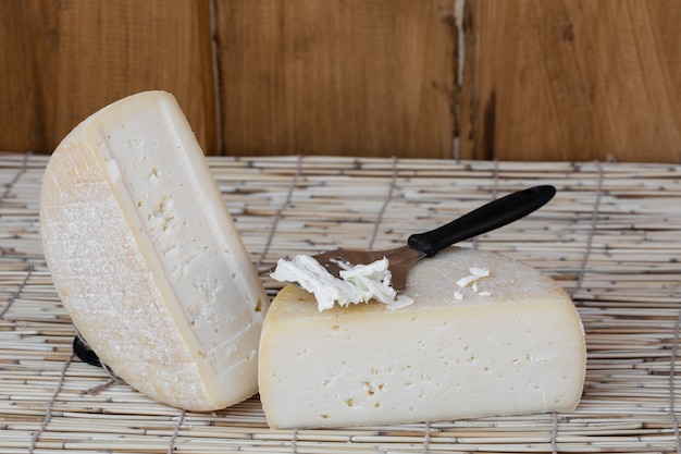 Foto fetta di formaggio a pasta dura, taglio di latte di capra con coltello da formaggio