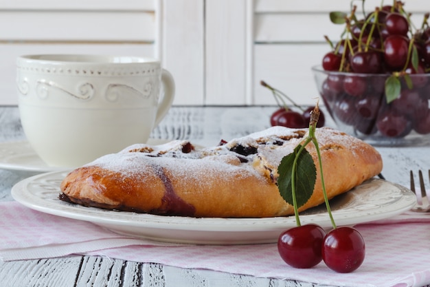 Slice of homemade cherry pie, cup of coffee, bowl with cherries