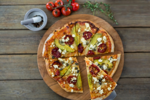 Slice of italian pizza served in a chopping board with ingredients