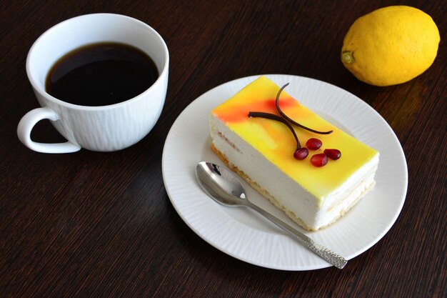 slice of lemon cake on white saucer with cup of coffee