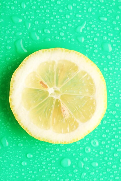 Foto fetta di limone con goccia su sfondo verde