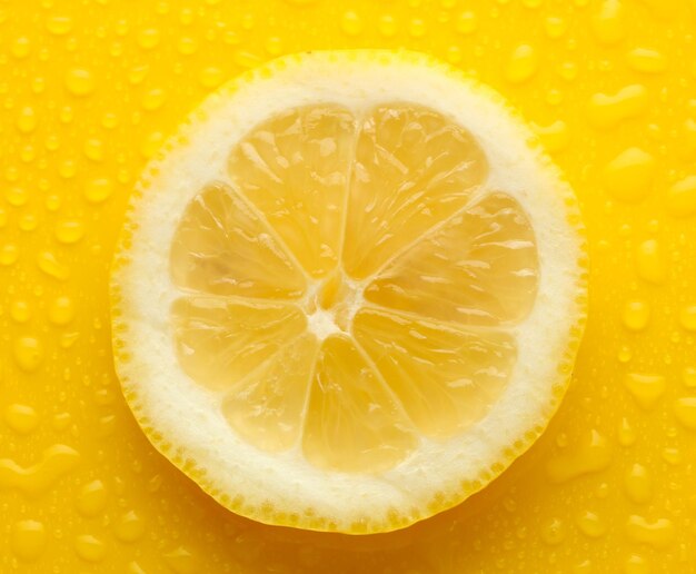 Slice of lemon with drop on yellow background