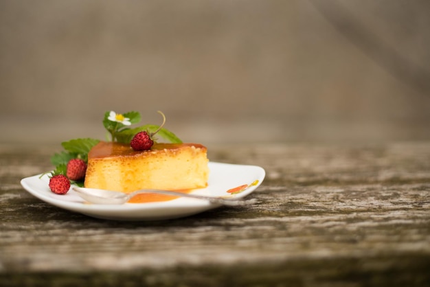 Slice of milk pudding with mint and strawberries over a wooden table b