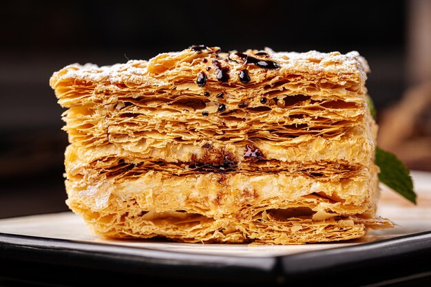 Slice of napoleon cake on wooden background