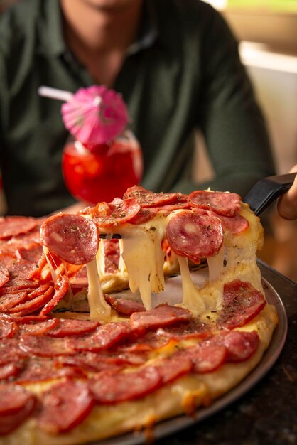 写真 サラミピザのスライスが引っ張られチーズが伸びている