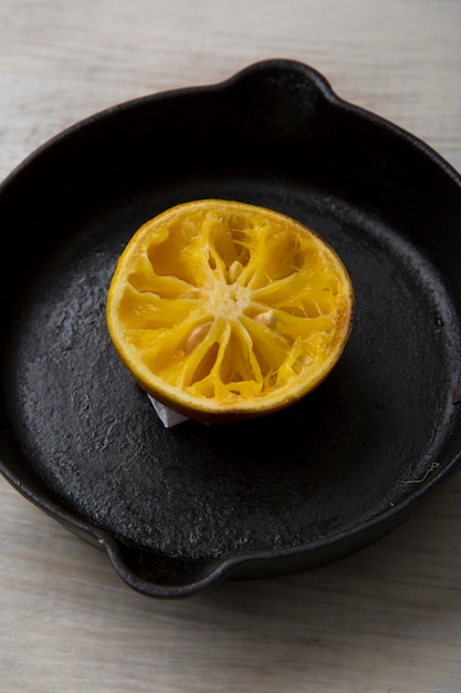 木製の床の鉄鍋にオレンジ色の生の果物のスライス